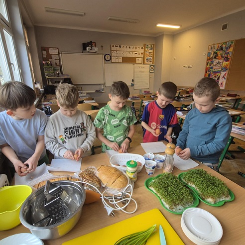 Grupa chłopców pracuje przy stole z produktami spożywczymi..jpg