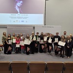 Grupa uczniów wraz z organizatorami stoi na scenie.jpg
