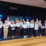 Grupa uczniów pozuje na scenie z dyplomami..jpg