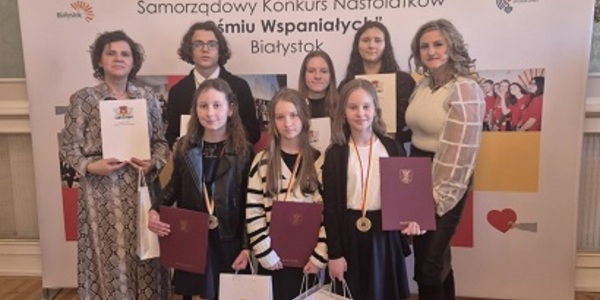 Grupa uczniów stoi razem z dwiema paniami. Wszyscy trzymają dyplomy i papierowe torby..jpg