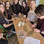 Grupa dziewczyn i chłopak siedzą przy stole z monetami.jpg