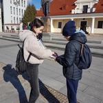 Dwoje uczniów pochyla się nad kartką przy pomniku.jpg