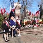 Poczet sztandarowy stoi przy pomniku z kwiatami.jpg