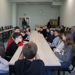 Grupa uczniów siedzi przy długim stole