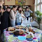 Grupa uczniów stoi przy stole z ciastami