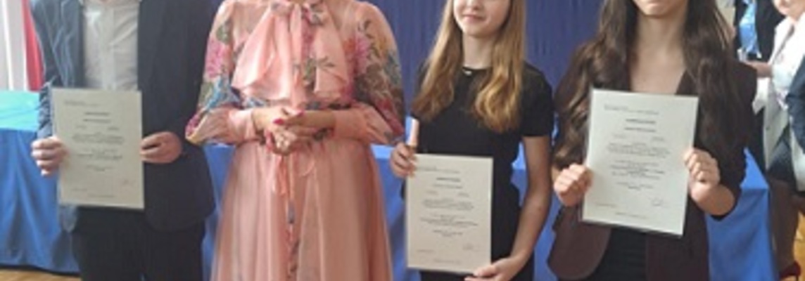 Troje uczniów stoi obok kobiety ubranej w kolorowa sukienkę..jpg