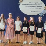 Grupa uczniów stoi w szeregu razem z kobietą w kolorowej sukience..jpg