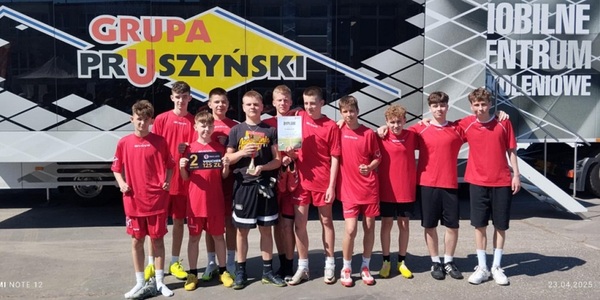 Grupa uczniów ubranych w sportowe stroje stoi na tle baneru..jpg