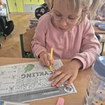 Dziewczynka w różowej bluzie uzupełnia kartę pracy.jpg
