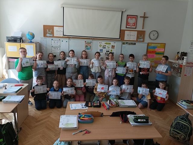 Grupa dzieci trzyma karty pracy w rękach..jpg