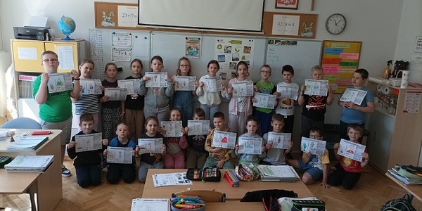 Grupa dzieci trzyma karty pracy w rękach..jpg