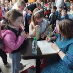 Grupa dzieci stoi przy pani podpisującej książki..jpg