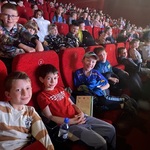 Grupa dzieci siedząca w czerwonych fotelach w kinie.jpg