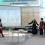 Grupa ucnziów przebrana w szlacheckie stroje stoi na tle ekranu z prezentacją.JPG