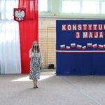 Kobieta przemawia przez mikrofon_ w tle flaga Polski oraz napisy biało-czerwone na niebieskim tle..JPG