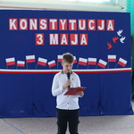 Uczeń czyta do mikrofonu przy tablicy z biało-czerwonymi napisami.JPG