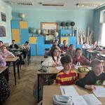 Uczniowie siedzą w ławkach w klasie i patrzą na ekran.jpg