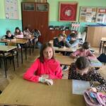 Uczniowie siedzą w ławkach w klasie i uzupełniają karty pracy.jpg