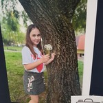 Dziewczynka stoi  z dmuchawcem przy drzewie.jpg