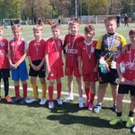 Grupa chłopców w czerwonych strojach sportowych pozuje na boisku do piłki nożnej..jpg