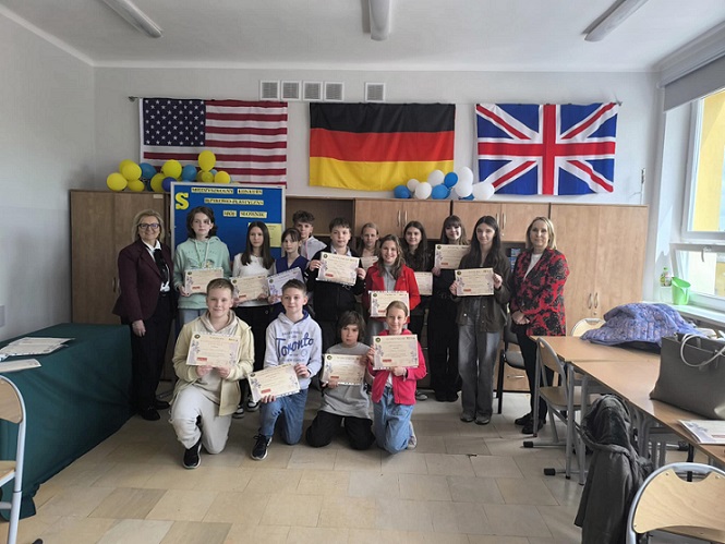 Grupowe zdjęcie uczniów z dyplomami . W tle falgi UK_ USA i Niemiec.jpg