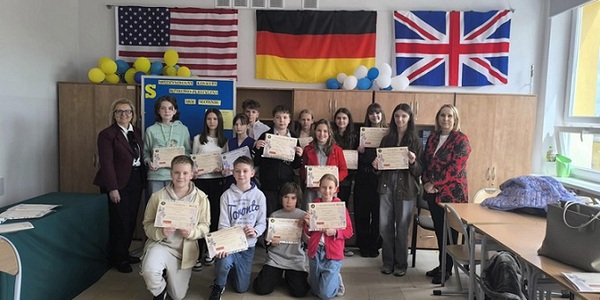 Grupowe zdjęcie uczniów z dyplomami . W tle falgi UK_ USA i Niemiec.jpg