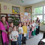 Grupa dzieci pozuje z dwiema paniami do zdjęcia w bibliotece.  W rękach trzymają dyplomy.jpg