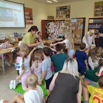 Nauczycielki częstują lizakami uczniów_ którzy siedzą na podłodze w biboliotece.jpg