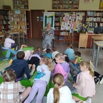 Pani Dyrektor czyta  książkę dzieciom_ które leżą lub siedzą na podłodze w biboliotece.jpg