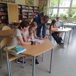 Uczniowie w bibliotece  pochylają się nad kartkami .jpg
