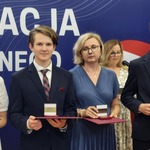 Kobieta i chłopak pozują do zdjęcia z medalami w rękach.