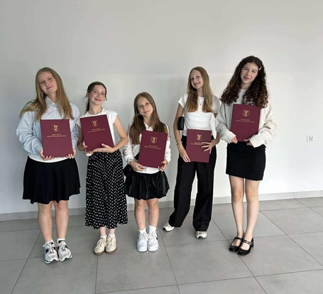 Pięć dziewcząt pozuje do zdjęcia z dyplomami w rękach.jpg
