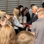 Mężczyzna w garniturze wręcza dyplomy uśmiechniętym dziewczynom.jpg
