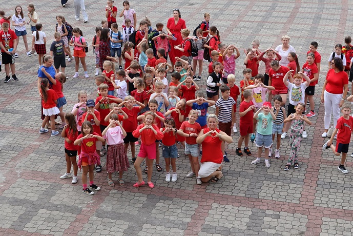 Grupa dzieci ubrana na czerwono pozuje do zdjęcia. Dzieci pokazują z rąk serca..jpg