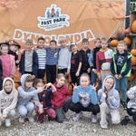 Grupa dzieci stoi lub siedzi przy banerze z dyniami..jpg