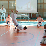 Sportowcy ubrani w białe kimona pokazują sztuczki na hali sportowej..jpg