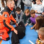 Po lewej ratownik w pomarańczowym uniformie klęczy na materacu_ przed nim leży człowiek ubrany na czarno..jpg