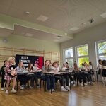 Grupa uczniów slacze wokół ławek_  w których siedzą starsi uczniowie.jpg