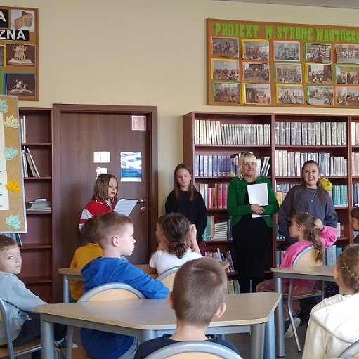 Dzieci słuchaja wierszy czytanych przez uczennicę w bibliotece szkolnej..jpg