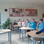 Dzieci stoją z jędna ręka w górze w bibilotece przed panią _ która do nich mówi..jpg