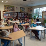 Grupa dzieci siedzi w ławkach w bibliotece.jpg
