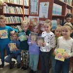 Grupa dzieci stoi wśród regałów z książkami.jpg