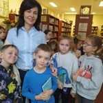 Kobieta w jasnej koszuli stoi z uczniami w bibliotece..jpg