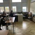 Uczniowie siedzący w szkolnych ławkach przed wyświetlanym tekstem na ekranie.jpg