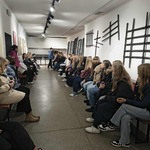Grupa uczniów siedzi wszdłuż ściany w pokoju.jpg