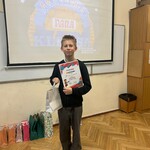Uczeń pozuje do zdjęcia z dyplomem i kolorową torebką..jpeg