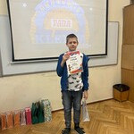 Uczeń pozuje do zdjęcia z dyplomem i kolorową torebką.jpeg