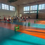 Duża grupa uczniów ćwiczy na sali gimnastycznej z niebiesko-pomarańczową podłogą..jpg
