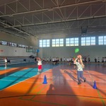 Duża grupa uczniów ćwiczyz balonami i piłkami na sali gimnastycznej z niebiesko-pomarańczową podłogą..jpg