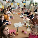 Grupa dzieci siedzi przy dużym stole w klasie i je kanapki z warzywami i owocami.jpg